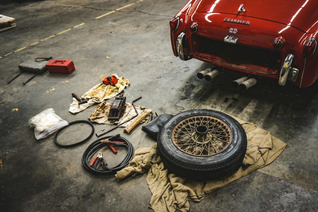 Vintage car undergoing tire replacement and maintenance in repair shop